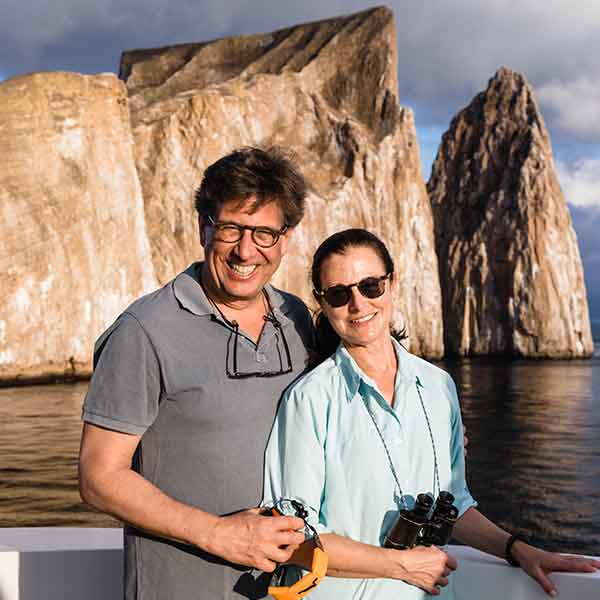 A man and woman are posing for a photo on a boat in the galapagos islands.