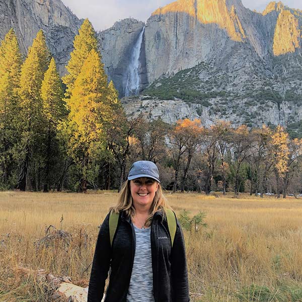 A woman standing in front of a waterfall in yosemite.