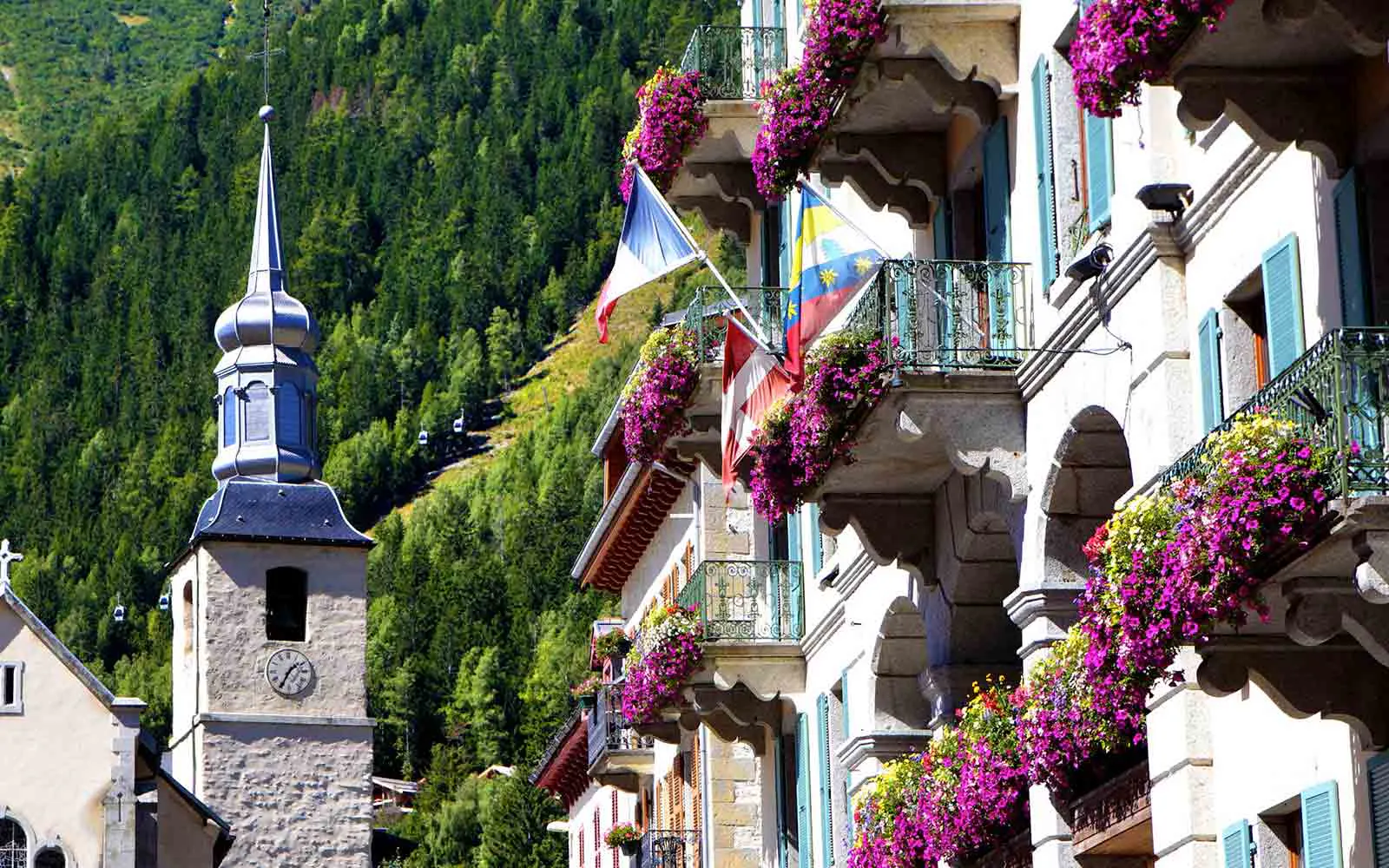 A picturesque building with a clock tower in the heart of the best alps hiking adventures, boasting beautifully adorned balconies adorned with vibrant flowers.