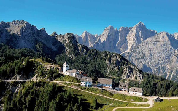 A picturesque mountain village nestled in the heart of the Dolomites, offering breathtaking alpine hiking adventures with a charming church in the background.