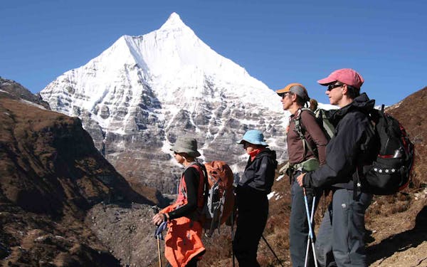 A group of people standing in front of a snowy mountain.