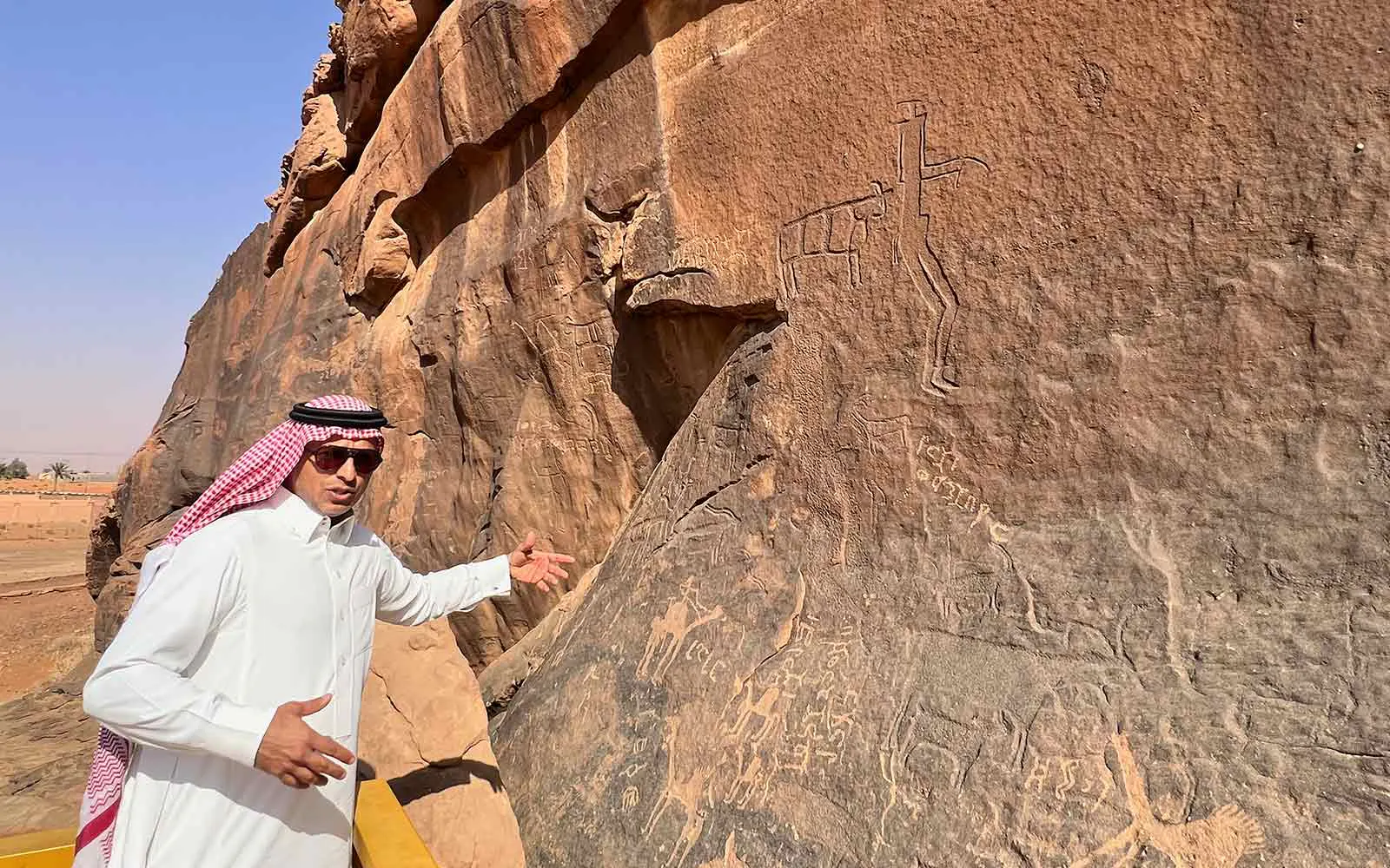 A man standing in front of a rock with writing on it.