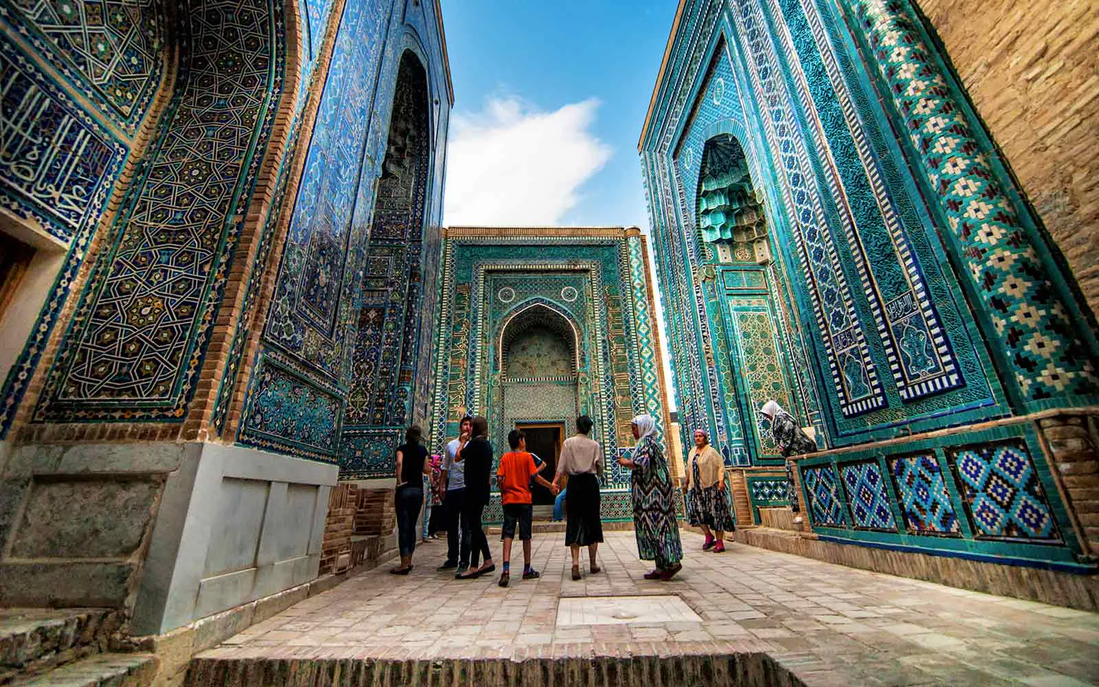 A group of people standing in a courtyard with blue tiled walls.