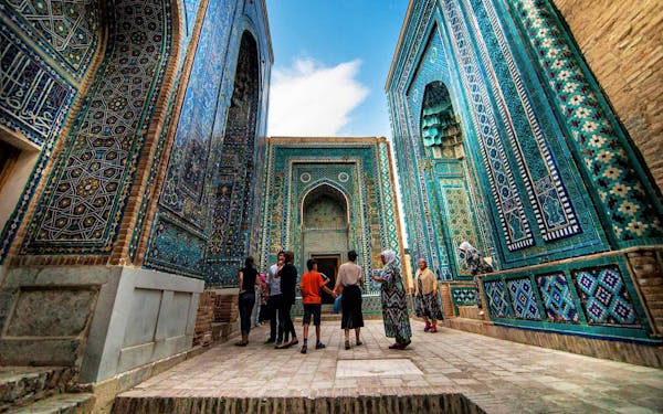 A group of people standing in a courtyard with blue tiled walls.