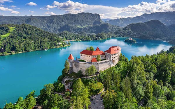 The castle on top of a mountain overlooking a lake in Bled, Slovenia offers breathtaking views for hiking enthusiasts exploring Europe's natural wonders.