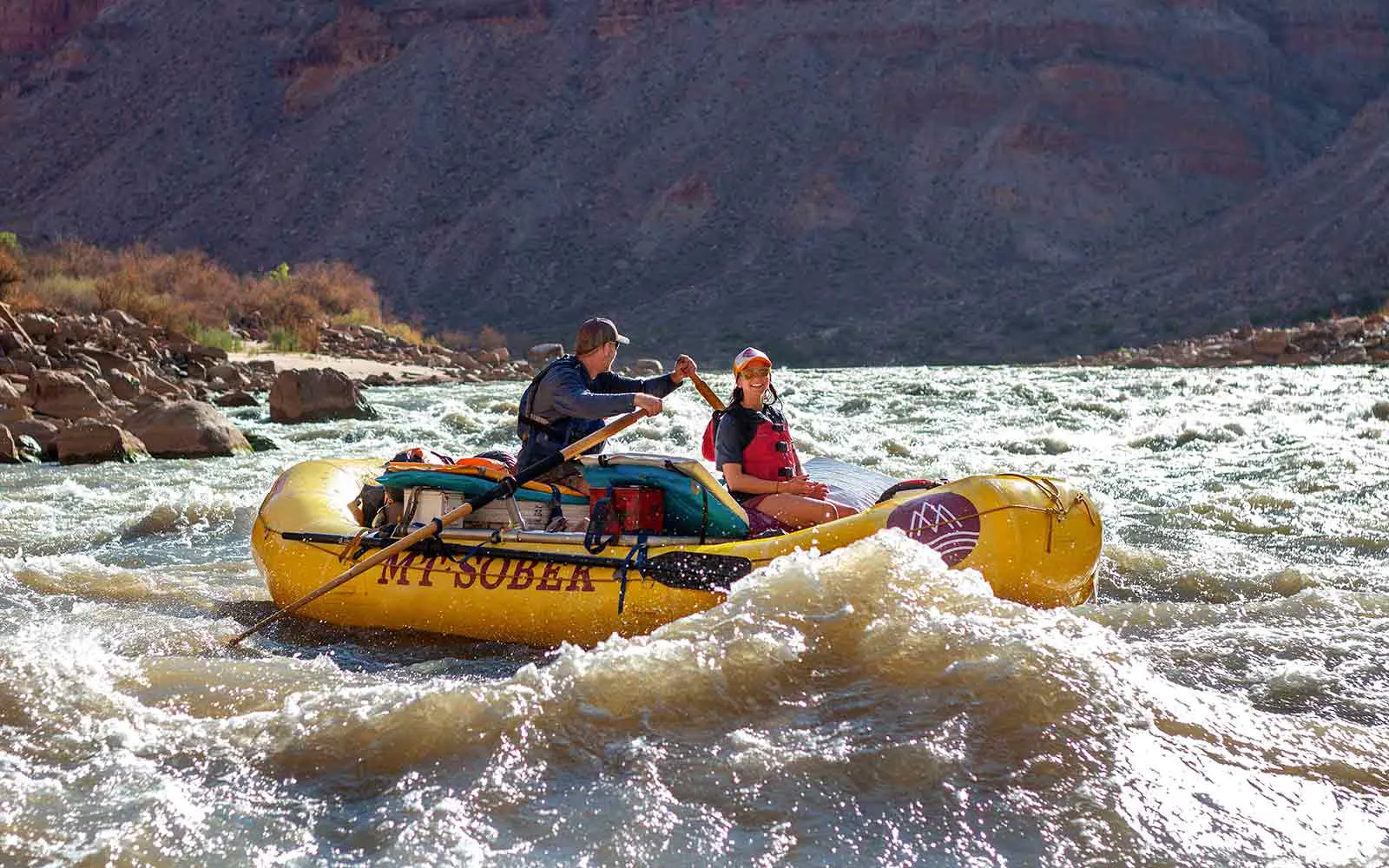 Two people engaging in river rafting in a yellow raft.