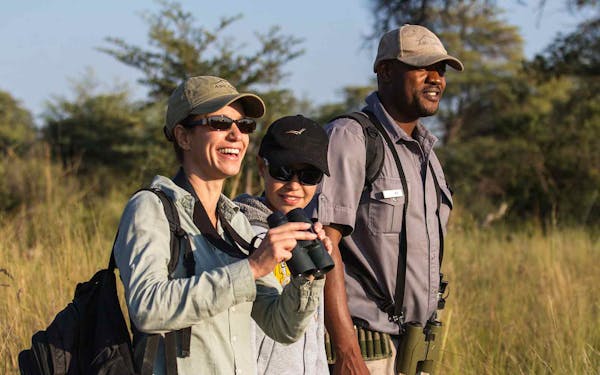 Wildlife enthusiasts with binoculars exploring a grassy field during a Safari adventure.