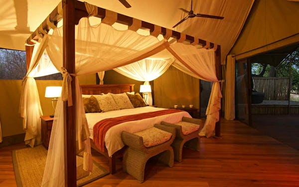 A wildlife safari adventure with a bed in a tent and a canopy over it.