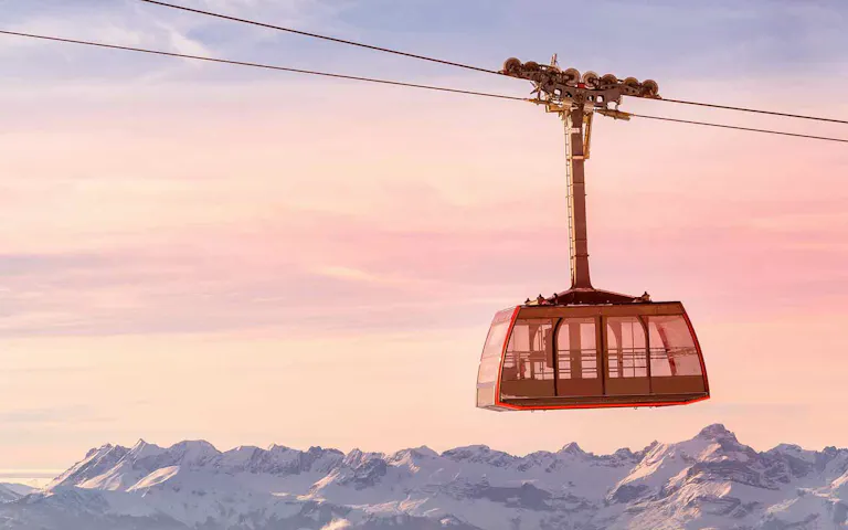 A cable car high up in the air with a beautiful view of the snowy Swiss Alps