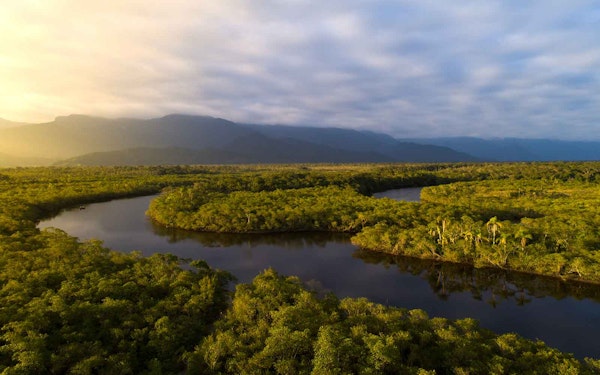 An aerial view of a river surrounded by trees and mountains.