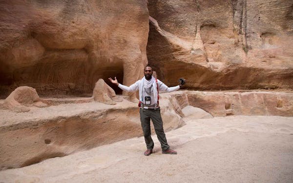 A man standing in front of a rock formation.