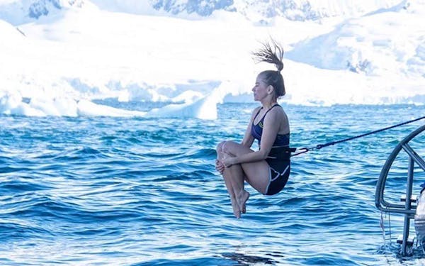 A woman is jumping off a polar cruise boat into the ocean.