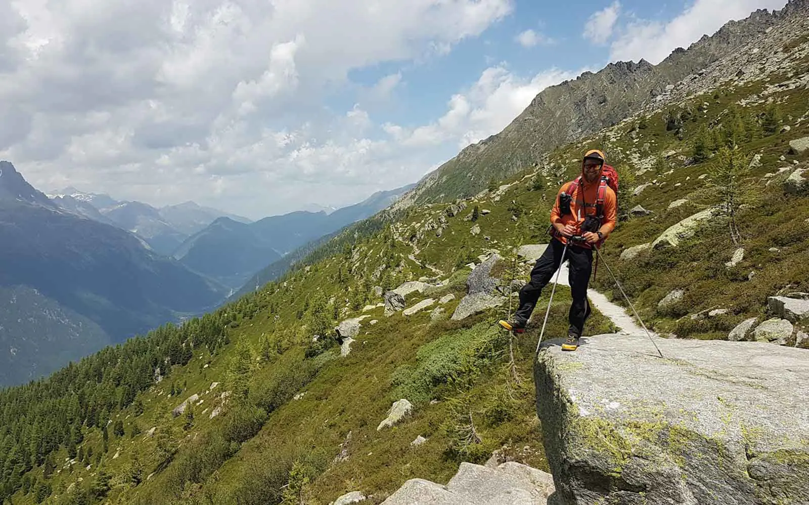 A man is standing on top of a rock in the stunning alps.