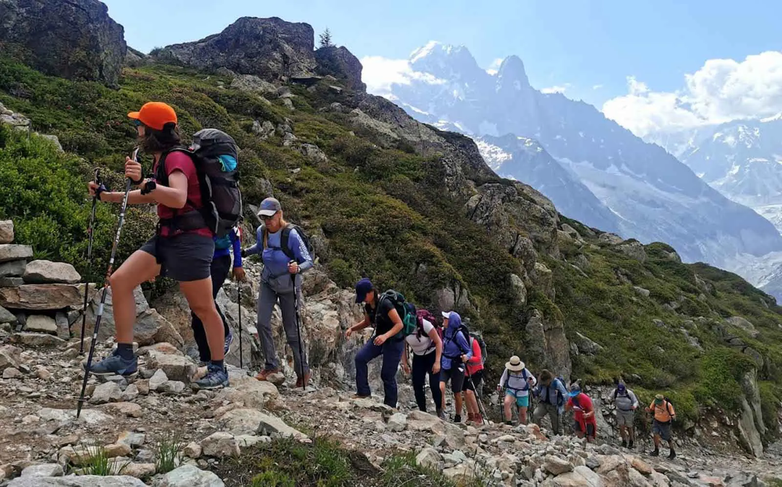 The best alps hiking adventures include a group of people hiking up a mountain trail.