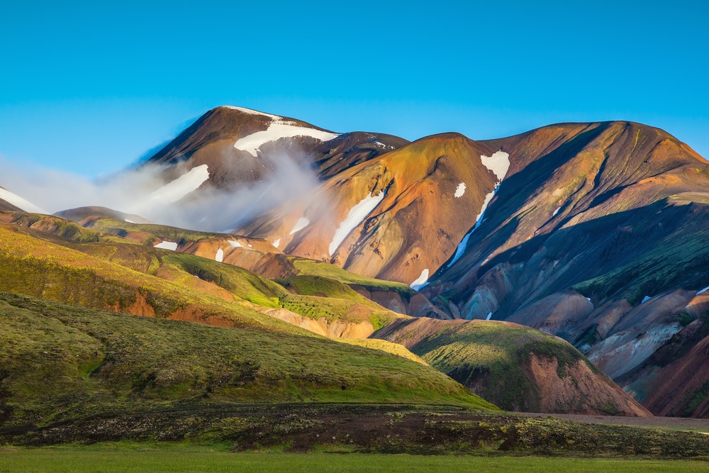 A colorful mountain with snow on it, perfect for hiking in Iceland.