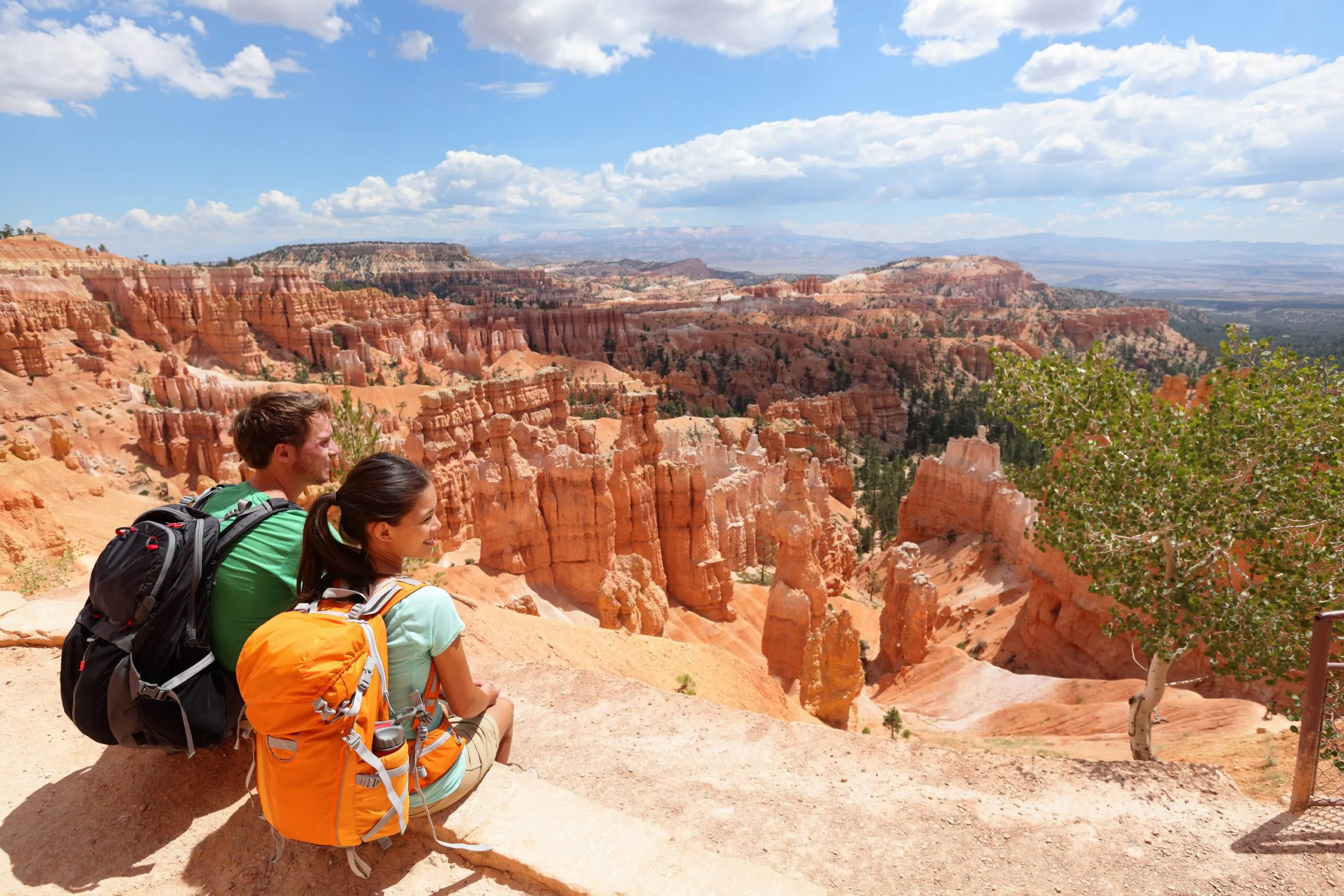 Two people sitting on a cliff overlooking bryce canyon national park in utah.