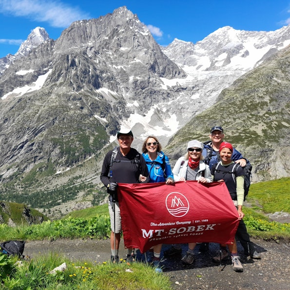 An adventure travel group standing in front of a majestic mountain.