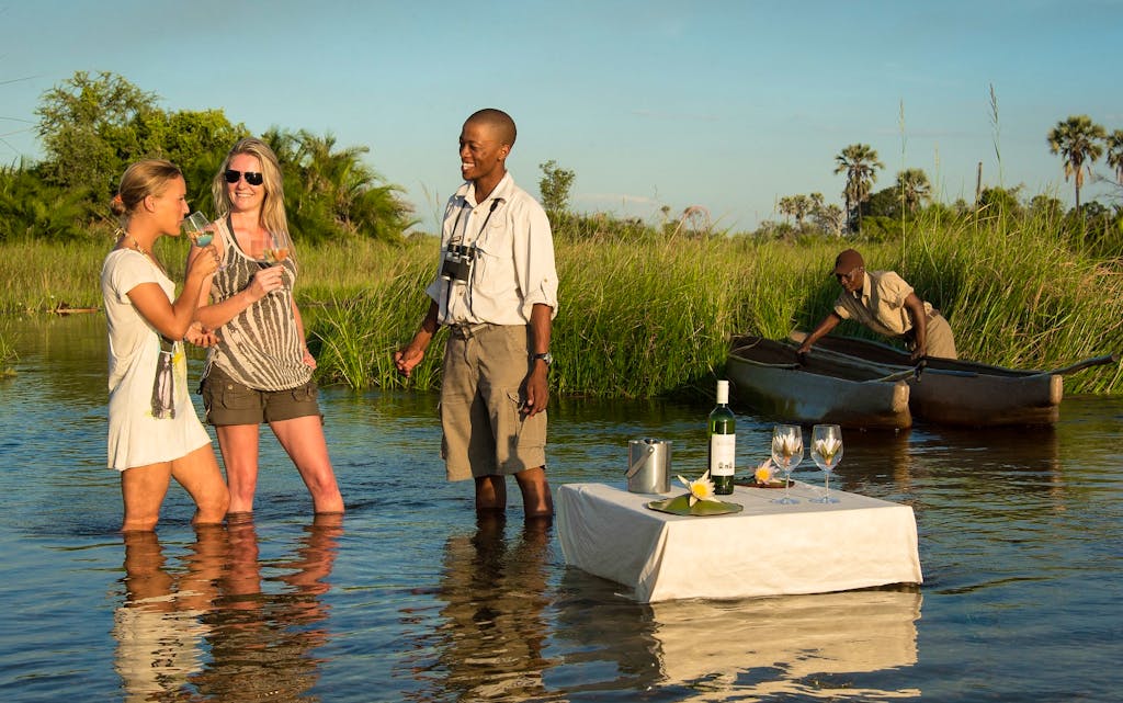 Guests enjoying floating cocktails at Xigera Camp. Okavango Delta, Botswana. 