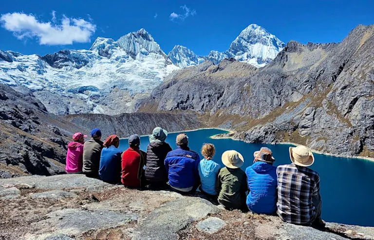 group of trekkers sitting gazing at the beauty of the majestic Cordillera Blanca in Peru, South America