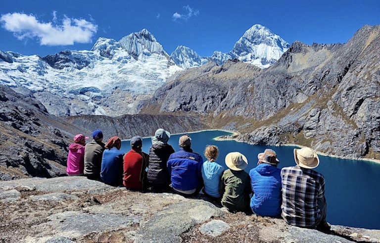 group of trekkers sitting gazing at the beauty of the majestic Cordillera Blanca in Peru, South America