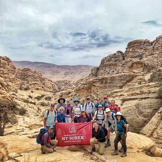 A group of people from an adventure travel company posing for a photo in the desert.