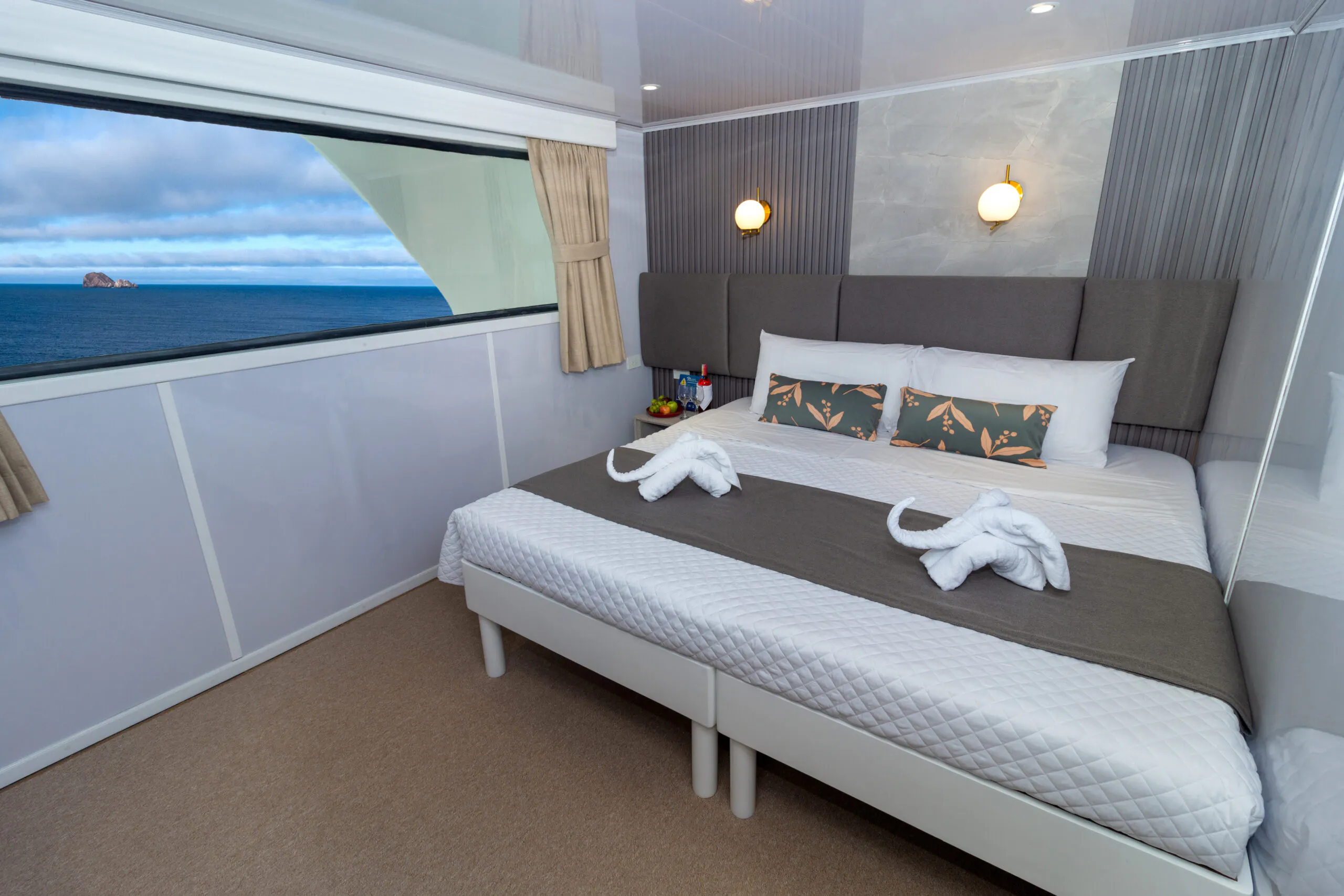 A bed in a room with a view of the ocean.