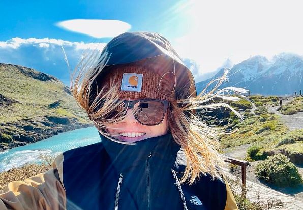 A woman is taking a selfie during her adventure travel in front of a magnificent mountain.