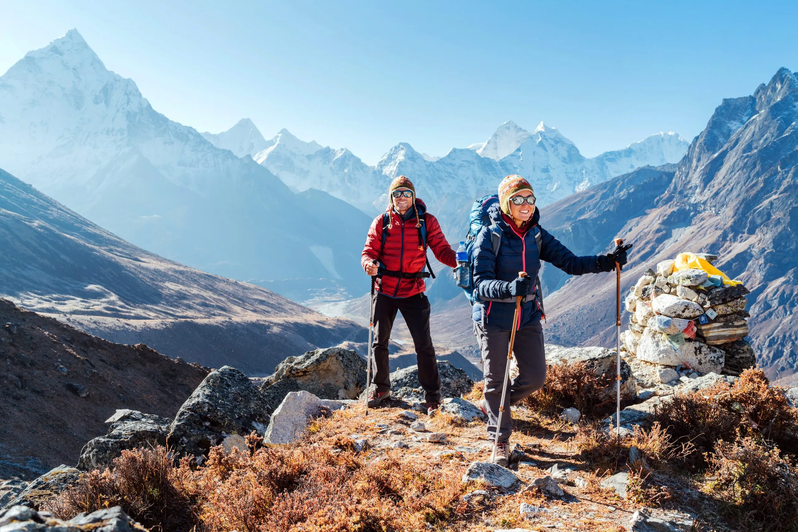 Couple following Everest Base Camp trekking route near Dughla 4620m. Backpackers carrying Backpacks and using trekking poles and enjoying valley view with Ama Dablam 6812m peak