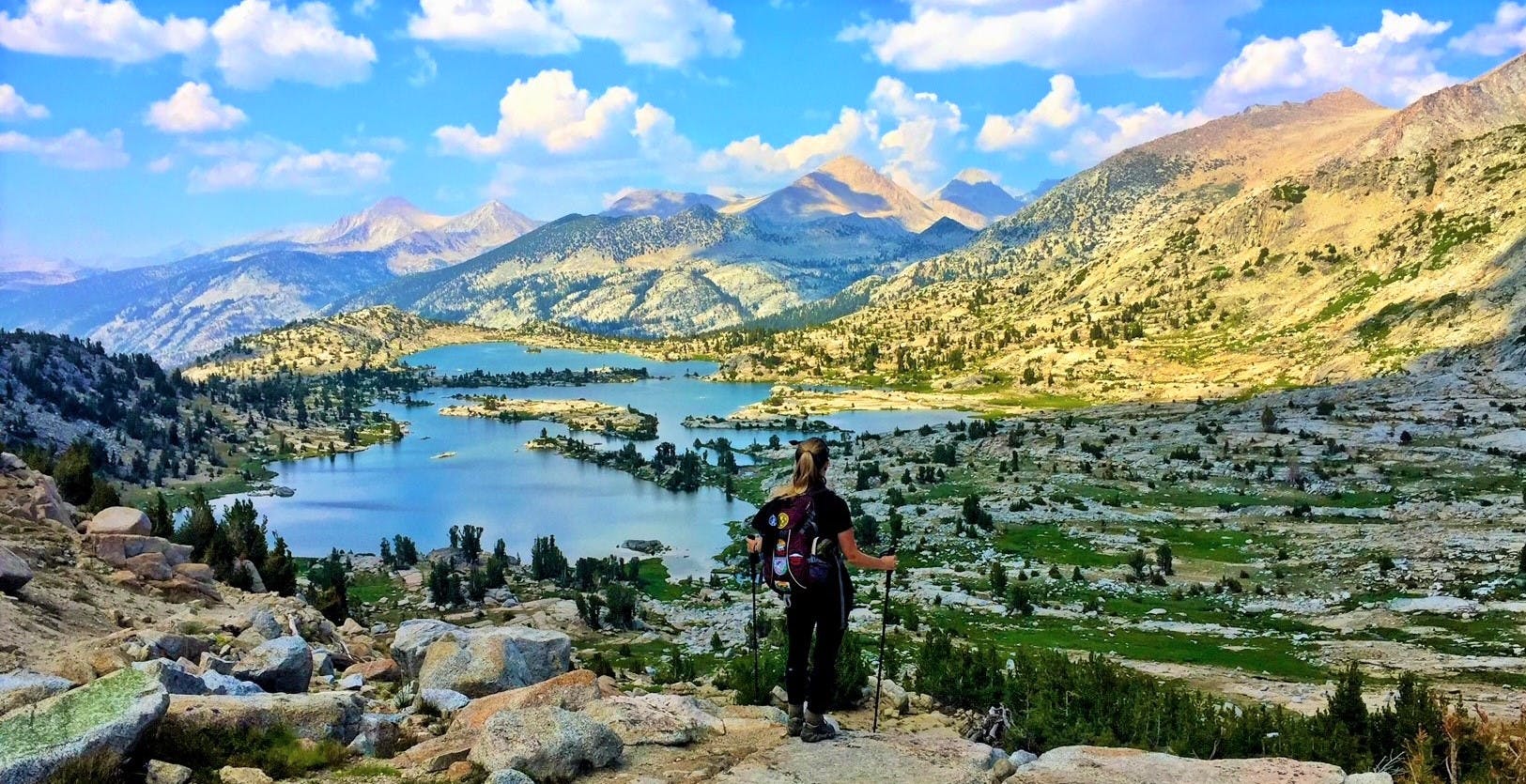 A woman hiking in the mountains near a lake.