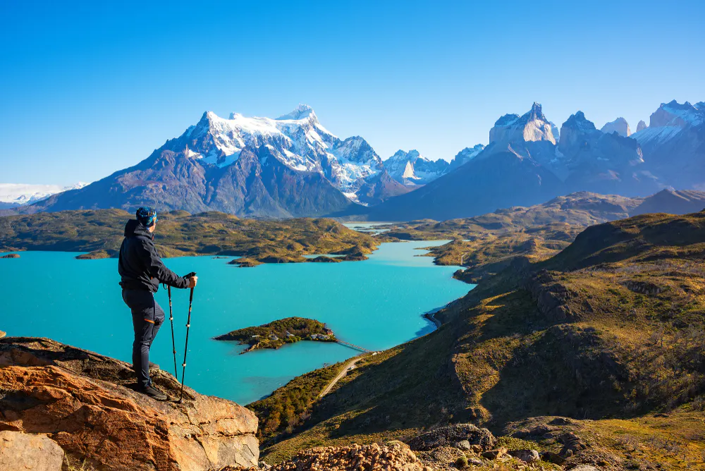 A man standing on top of a mountain overlooking a lake.