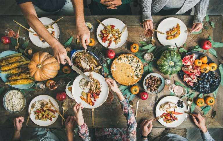 Traditional Thanksgiving day celebration party. Flat-lay of Friends or family eating different snacks and roast turkey or chicken at Festive Christmas table, top view
