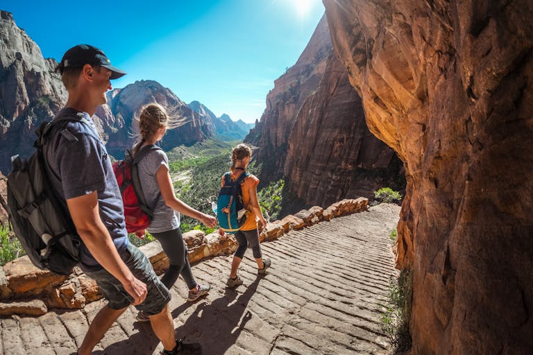 group of hikers walking down the stairs and enjoying view of Zion National Park