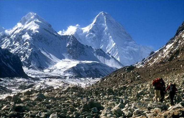 View of beautiful snowy Karakoram Range peaks in Pakistan with hikers in the foreground.