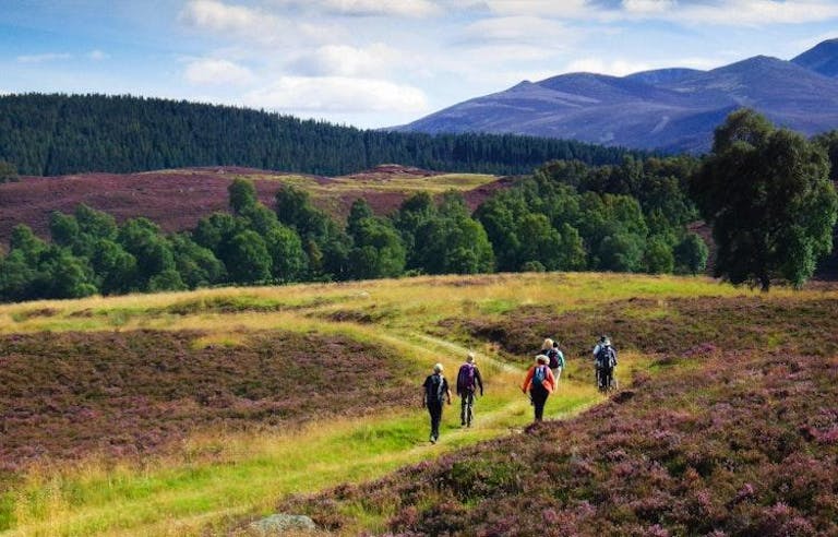 Group of hikers in a beautiful, grassy valley with mountains in the background in Scotland.