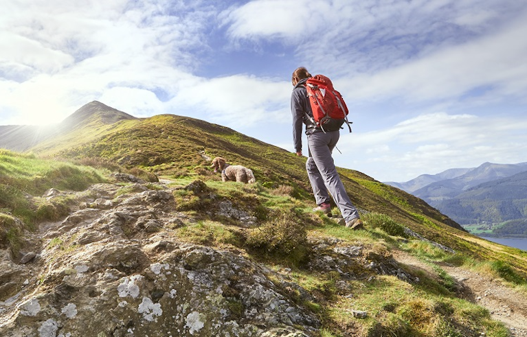 Man hiking beautiful grassy, green mountain in England