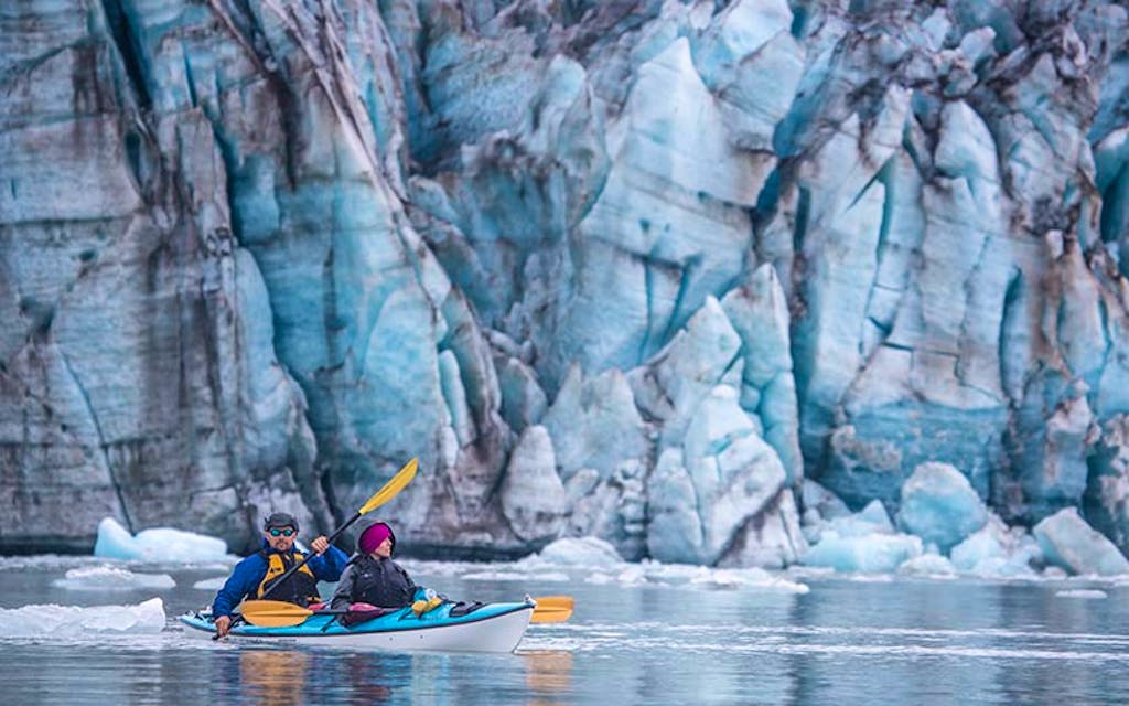 Tandem kayakers on river in Alaska near glaciers