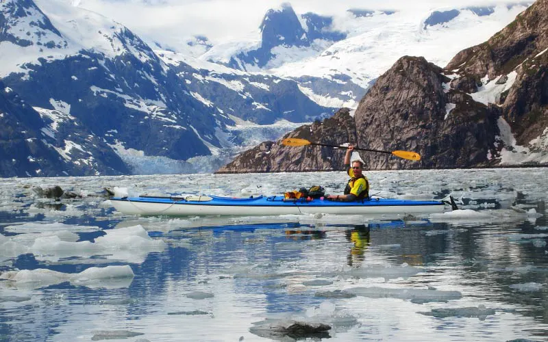 Tourists kayaking in the glacial waters of Alaska