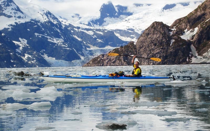 Tourists kayaking in the glacial waters of Alaska