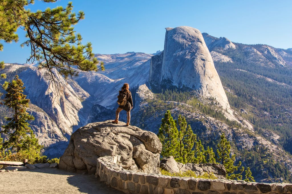 hiker looks at scenic mountain landscape of Yosemite, CA