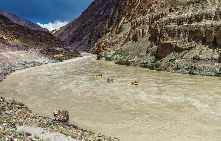 Three groups of people rafting down the Zanskar River in the Himalayan Mountains.