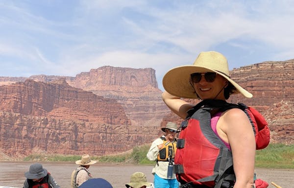 A woman wearing a hat on a raft in the grand canyon.