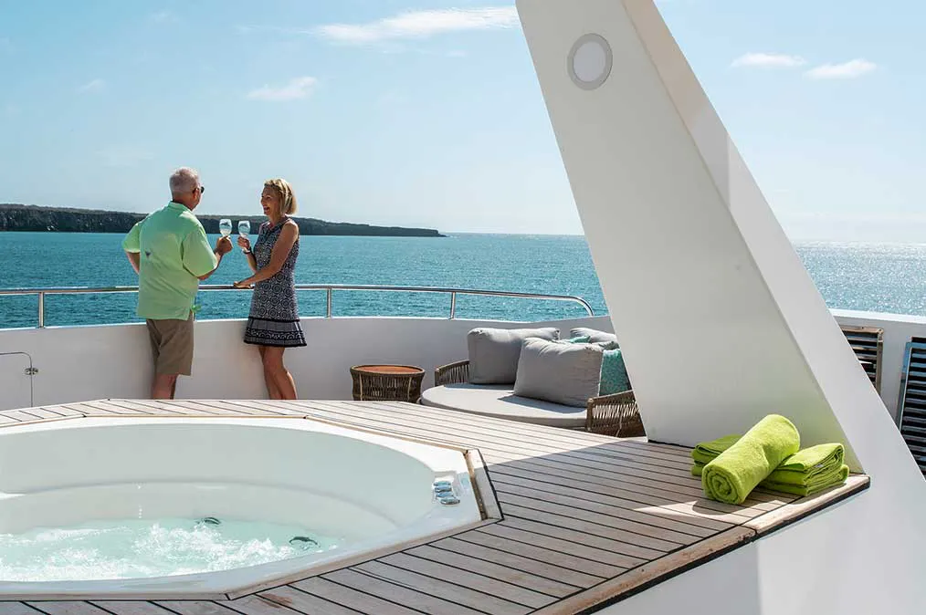 Two people standing on the deck of a boat with a hot tub.