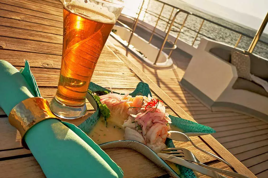 A glass of beer and a plate of food on a boat.