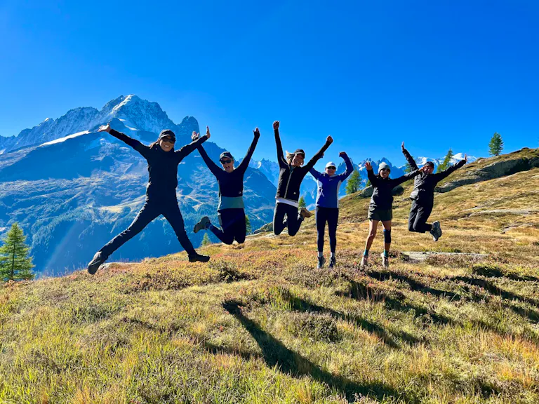 A group of people participating in a photo contest, joyfully jumping in the air against the backdrop of a majestic mountain.