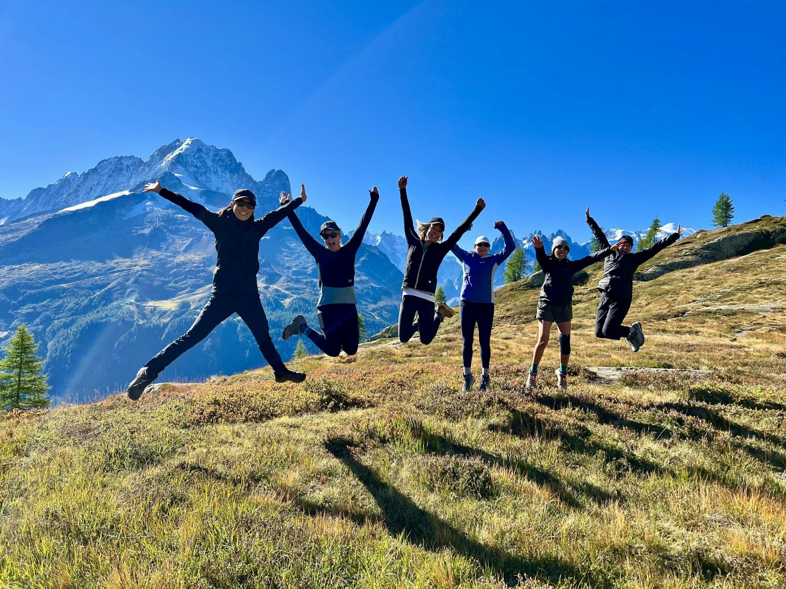 A group of people participating in a photo contest, joyfully jumping in the air against the backdrop of a majestic mountain.