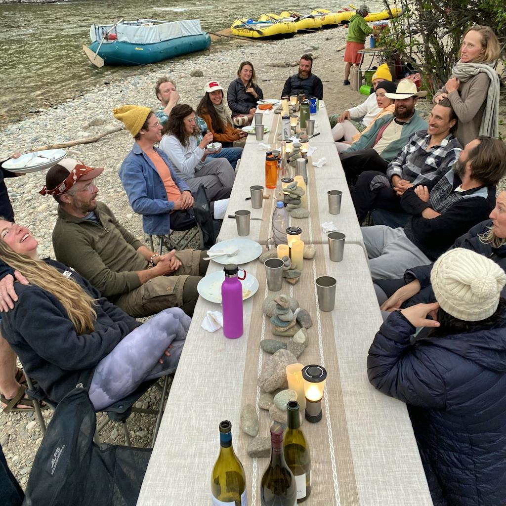Large group of travelers seated around a wide table in the Middle Fork of the Salmon River in Idaho