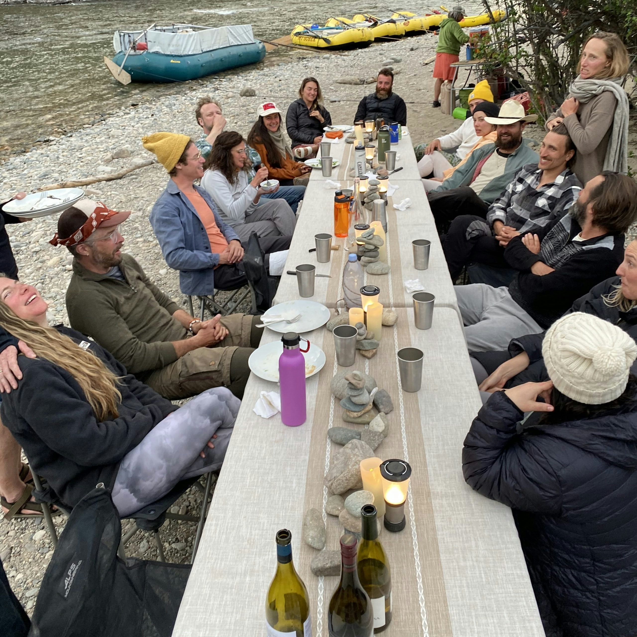 Large group of travelers seated around a wide table in the Middle Fork of the Salmon River in Idaho