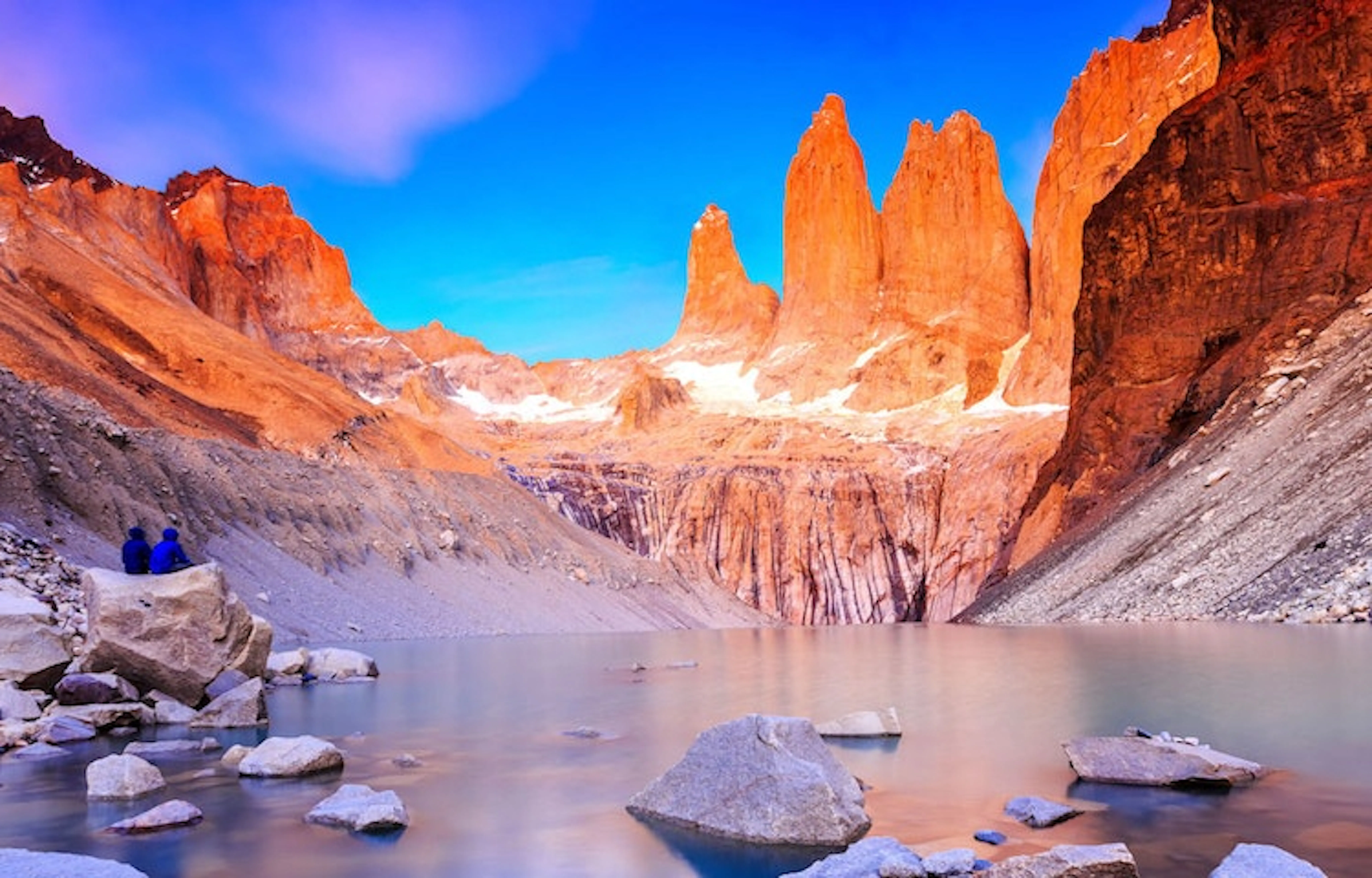A group of people standing in front of a majestic mountain lake, amidst one of the best hikes in Chile.