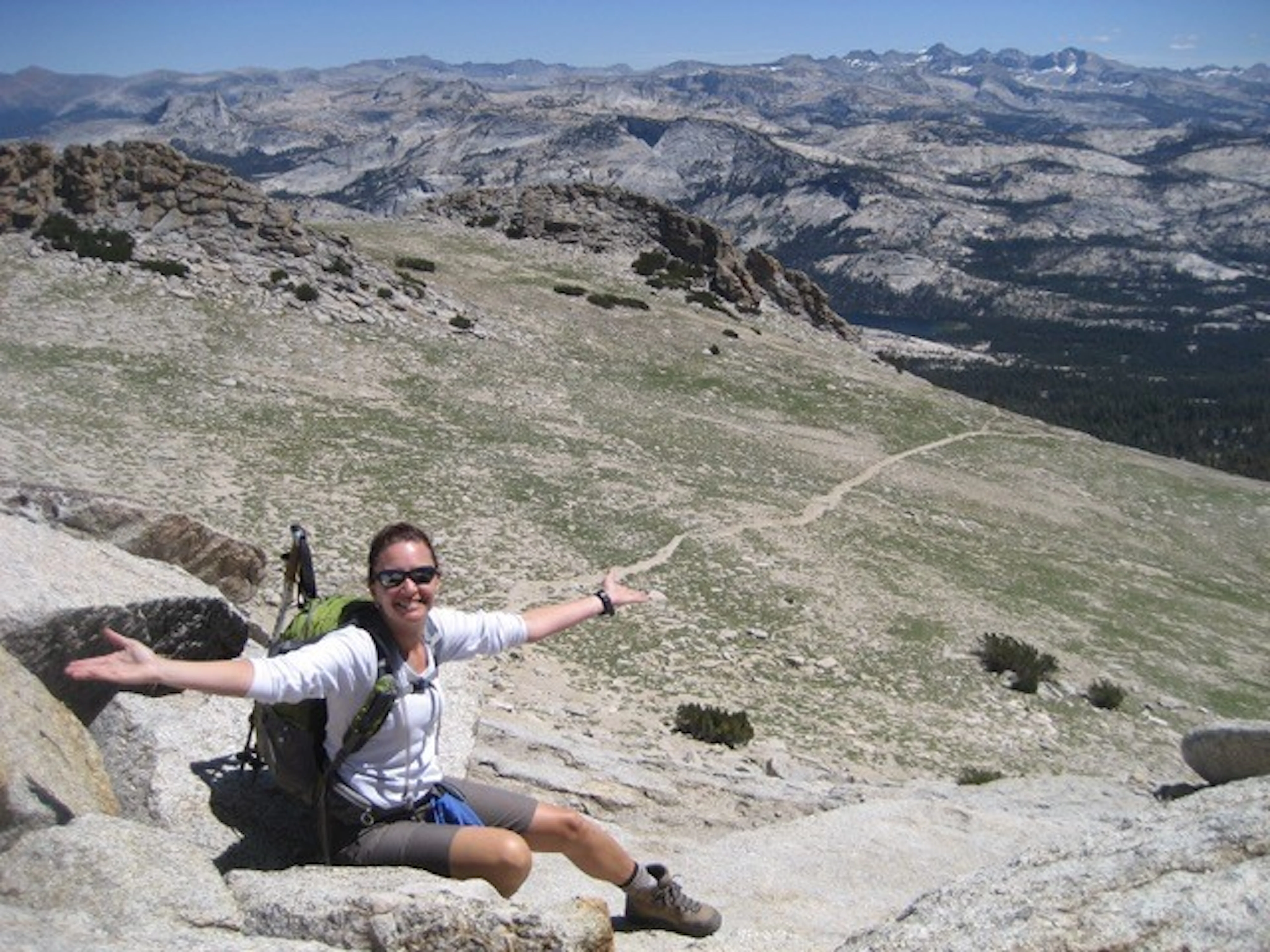 A woman standing on top of a mountain with her arms outstretched.