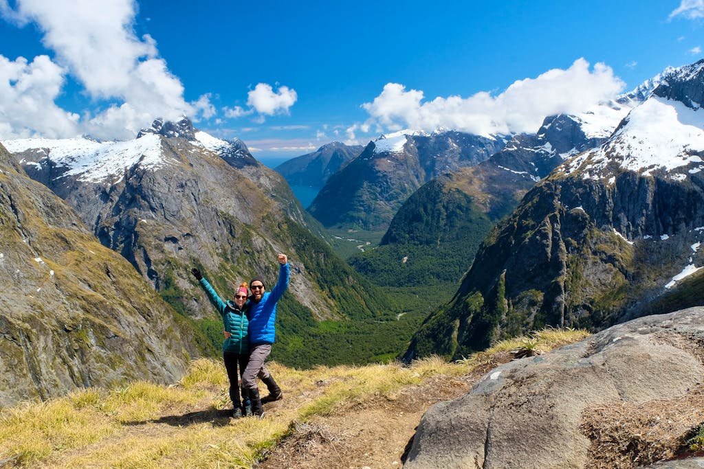 Two people male and female standing on top of a mountain in new zealand, europe
